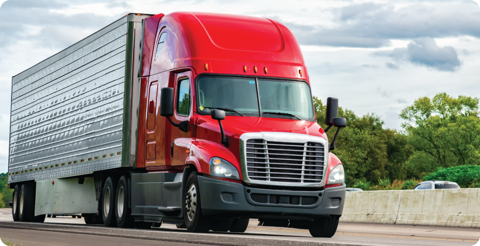 Red semi truck hauling freight in a dry van down the highway
