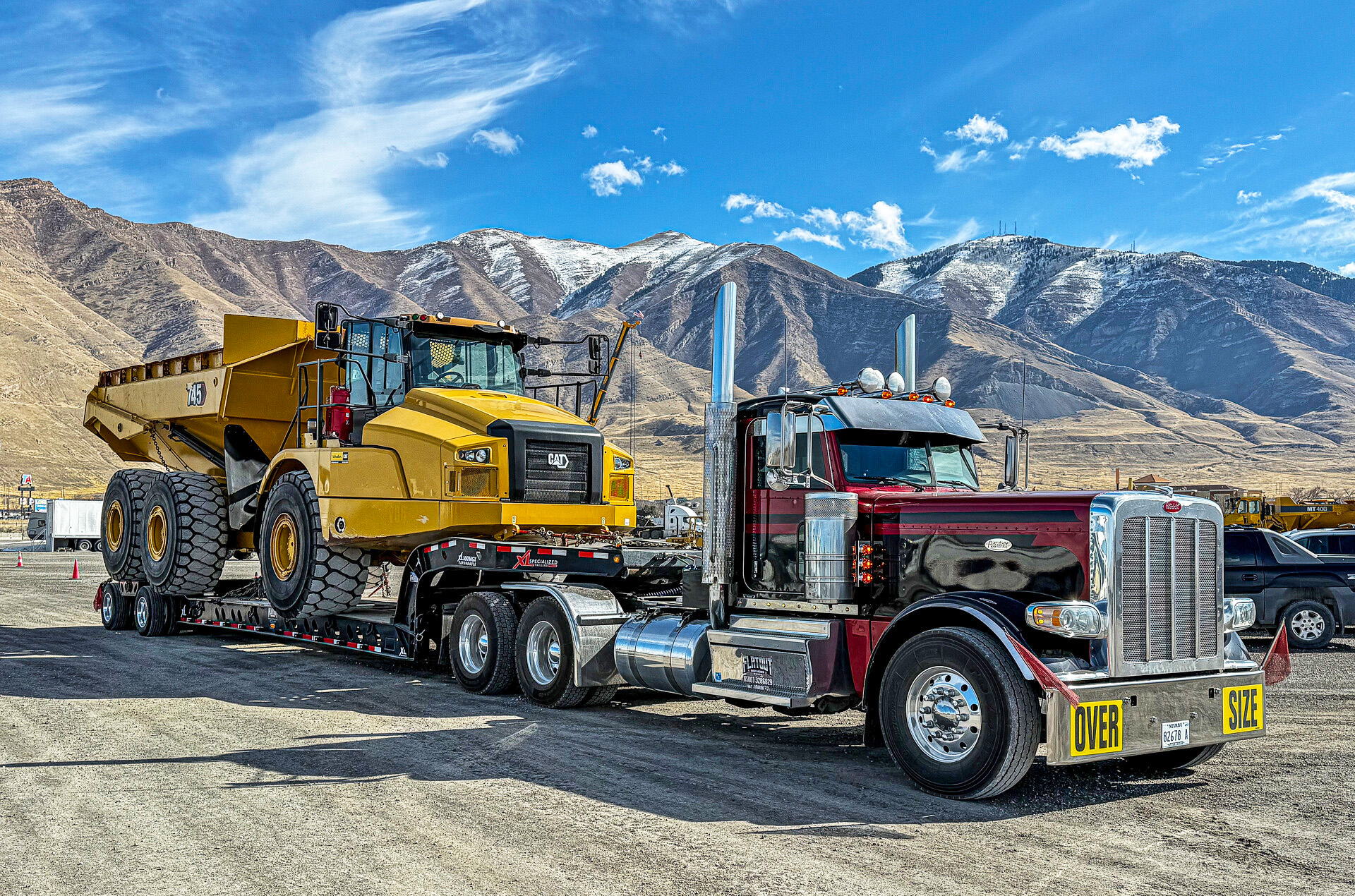 Flat_Out_Services1 Flat Out Servies truck of a heavy haul tractor and trailer. Truck is in front of a mountain range hauling a dump truck.