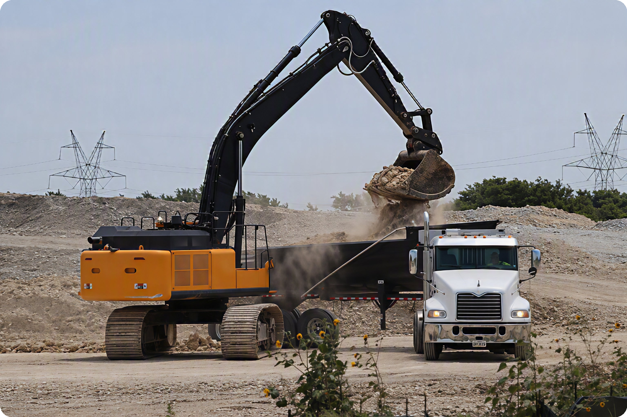 work_site_2_rounded_corners Excavator loading aggregate material into a dump truck at a quarry, supporting aggregate hauling and construction operations.